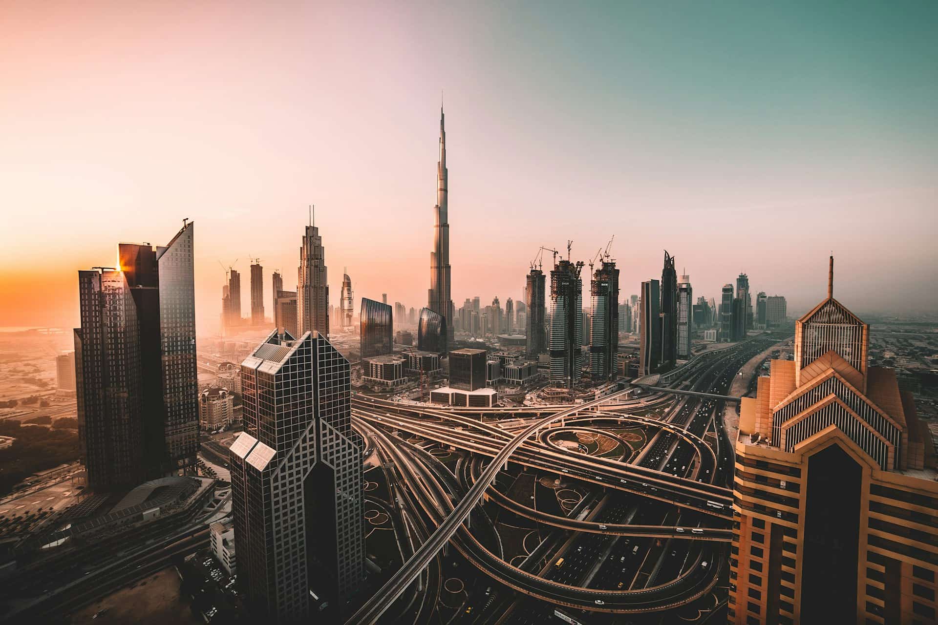 Aerial view of the Dubai skyline at sunset, with the Burj Khalifa above the Sheikh Zayed Road interchange